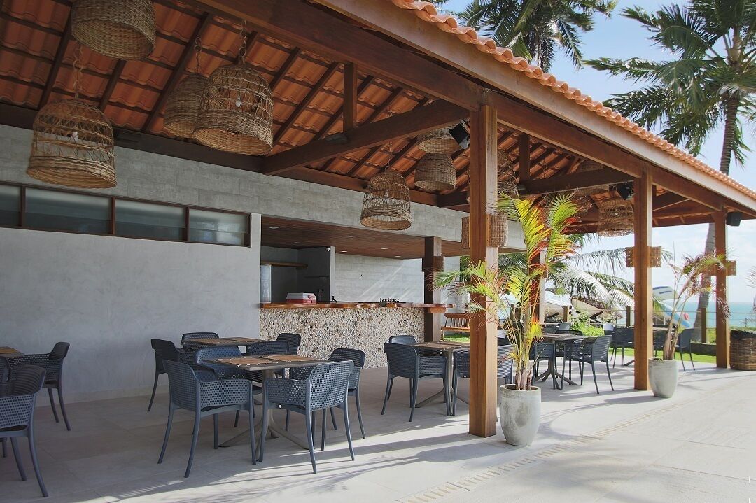 An outdoor dining area with wicker hanging lights, a concrete floor, and a view of the ocean.