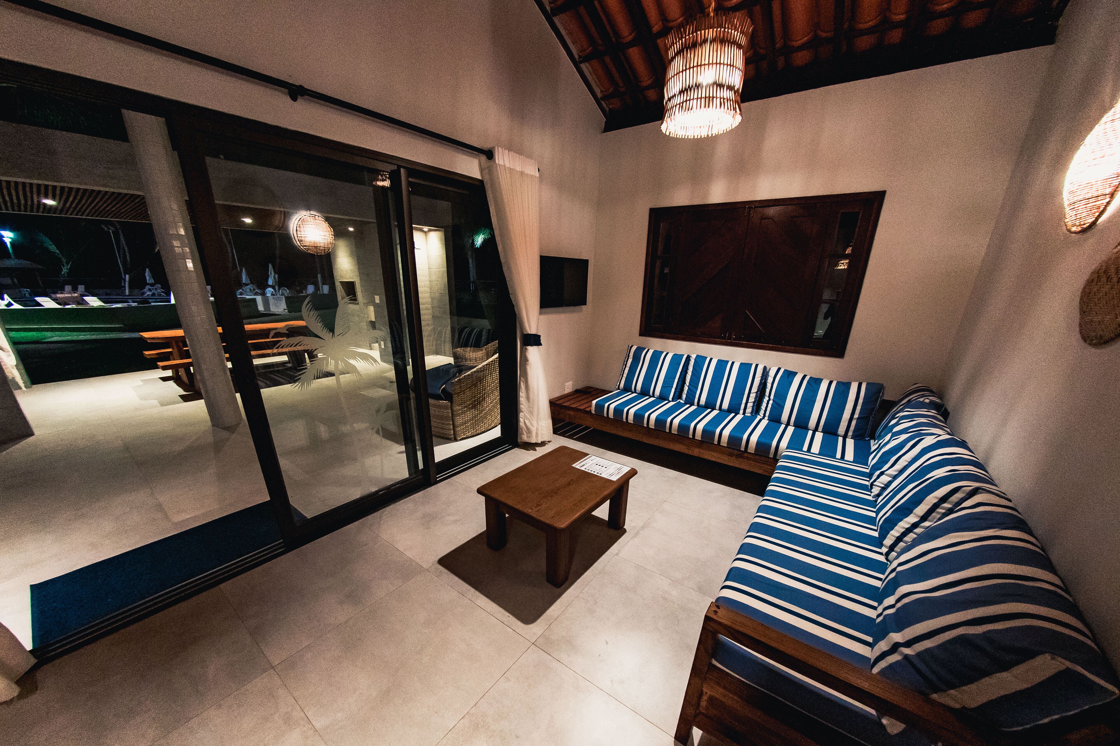 A modern living room with a sofa, a coffee table, and a glass door leading to an outdoor area.