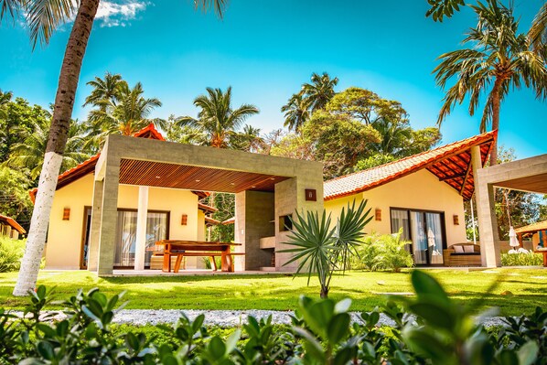 A modern resort with a covered outdoor seating area, palm trees, and a well-maintained lawn. - Costa Dourada Village (Maragogi)
