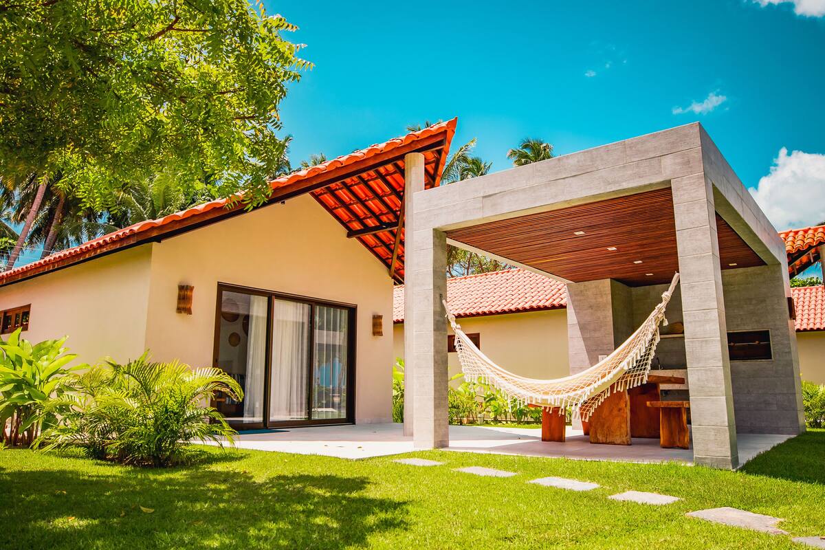 A modern house with a red-tiled roof, a hammock, and a patio area.