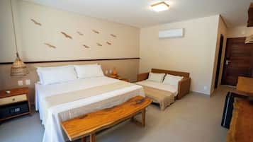 A bedroom with two beds, a bench, a bedside table, a hanging lamp, and a wall-mounted air conditioner.