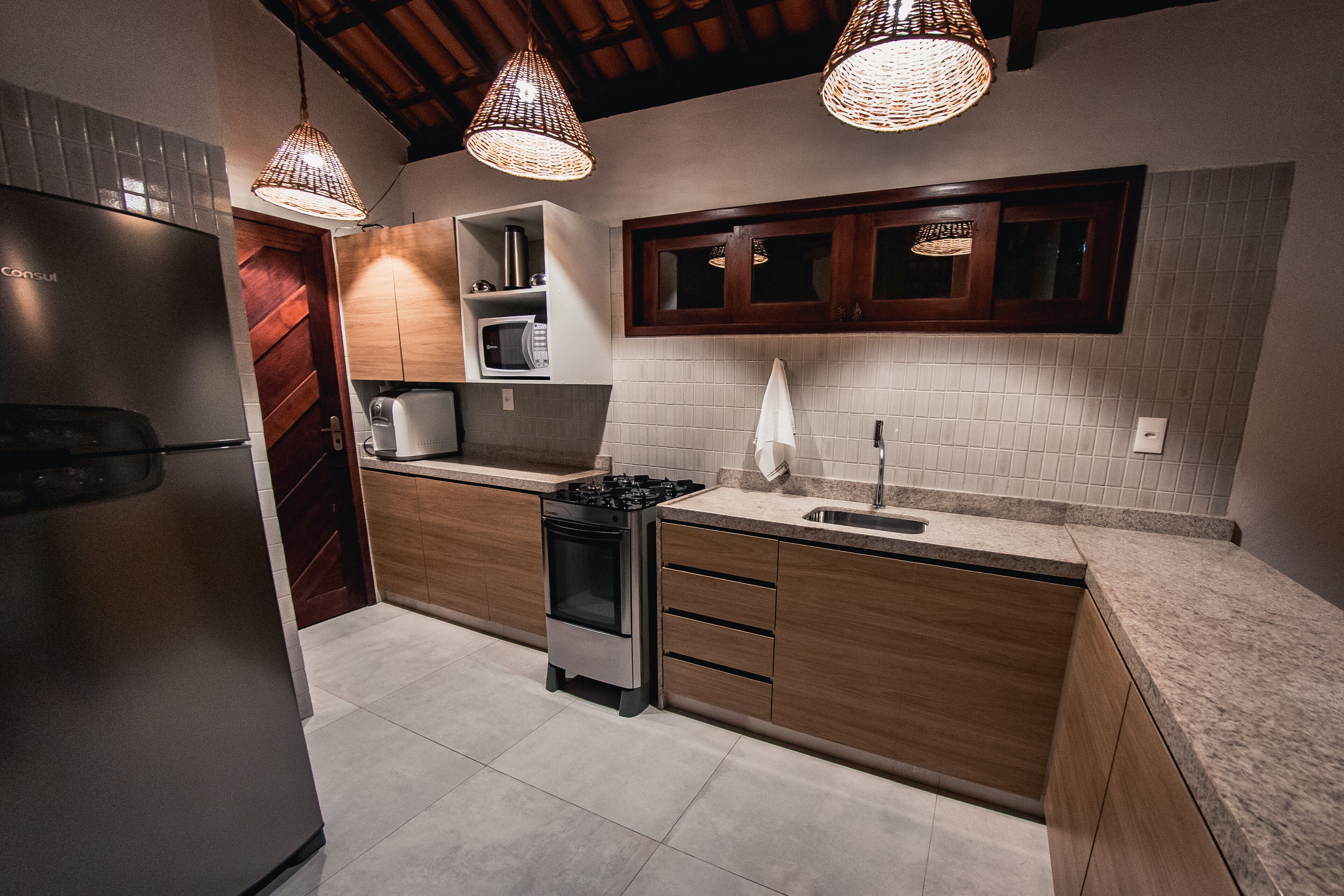 Una cocina moderna con refrigerador, estufa, microondas y gabinetes de madera.