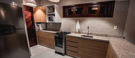 Una cocina moderna con refrigerador, estufa, microondas y gabinetes de madera.