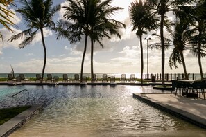 A pool area with lounge chairs and a view of the ocean. - Costa Dourada Village (Maragogi)