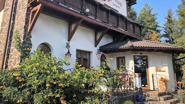 A traditional Alpine-style building with a stone facade, wooden balconies, and a sign reading "Pension Lampe". - Penzion Lampaš (Poprad)