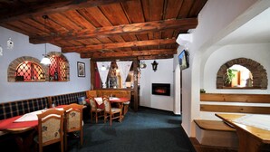 A cozy restaurant with wooden tables and benches, a fireplace, and arched windows. - Penzion Lampaš (Poprad)