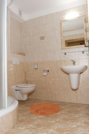 A bathroom with a toilet, sink, and mirror. - Penzion Lampaš (Poprad)