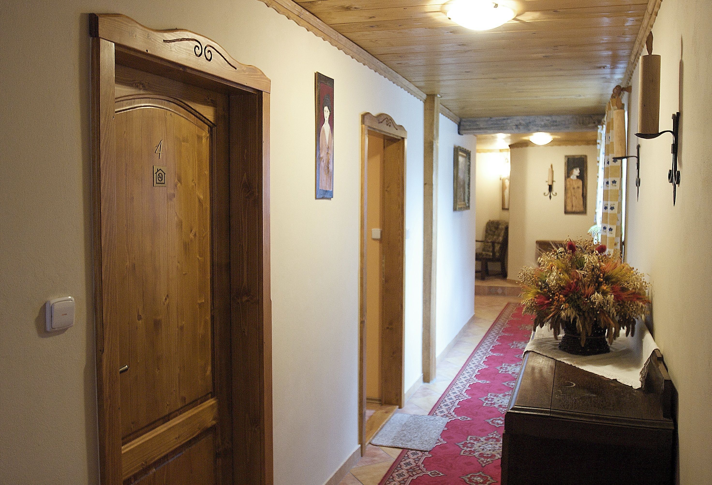 A hallway with wooden doors, a red patterned rug, and a potted plant.