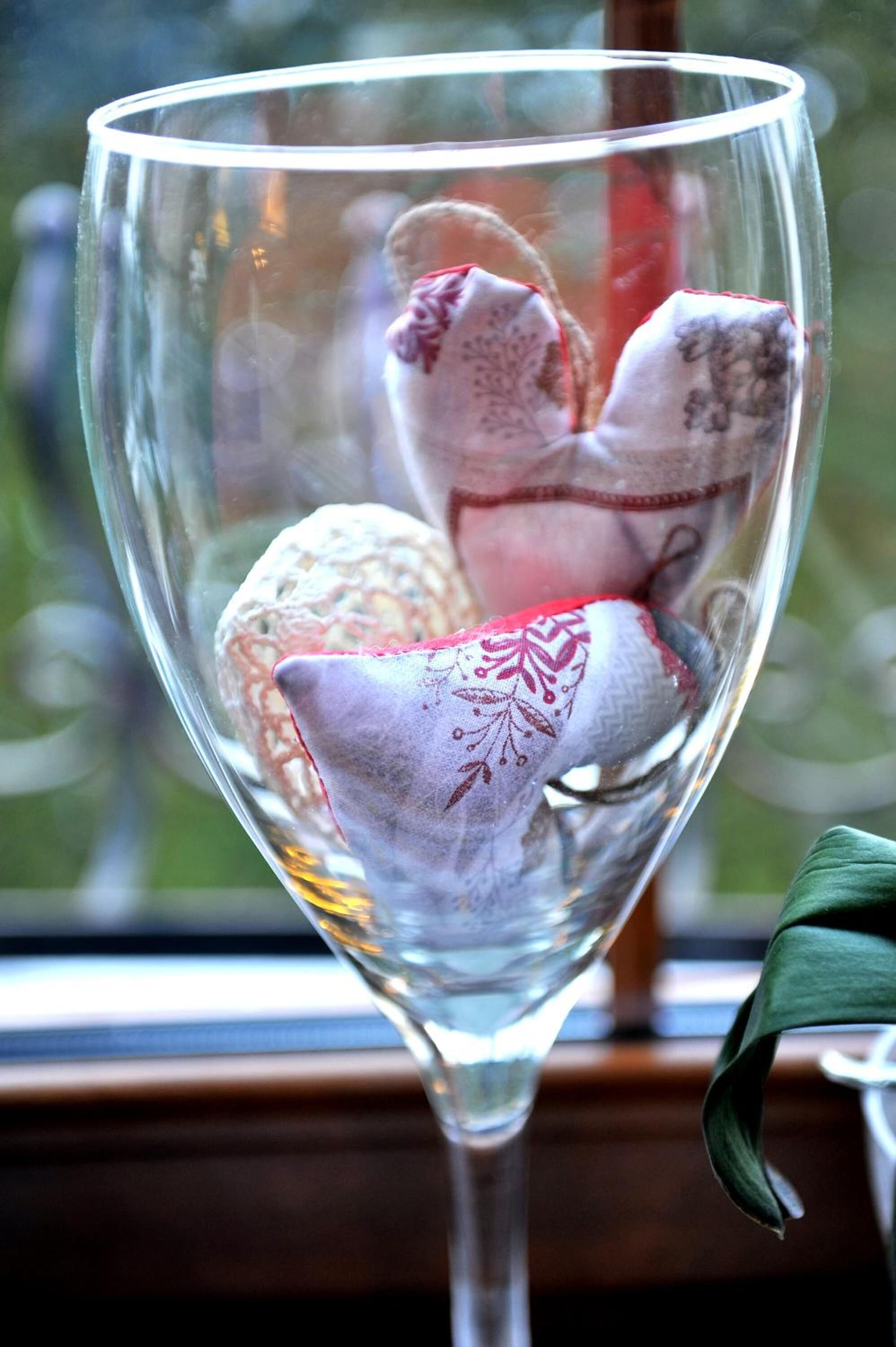 A clear glass vase with a decorative item inside, placed on a windowsill.