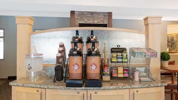 A coffee station with two espresso machines, a water dispenser, and a variety of coffee pods and syrups.