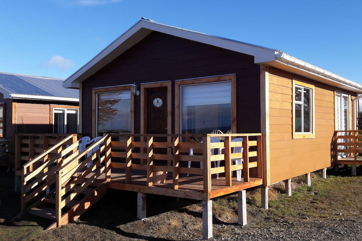 A wooden cabin with a porch and a staircase leading to the entrance.