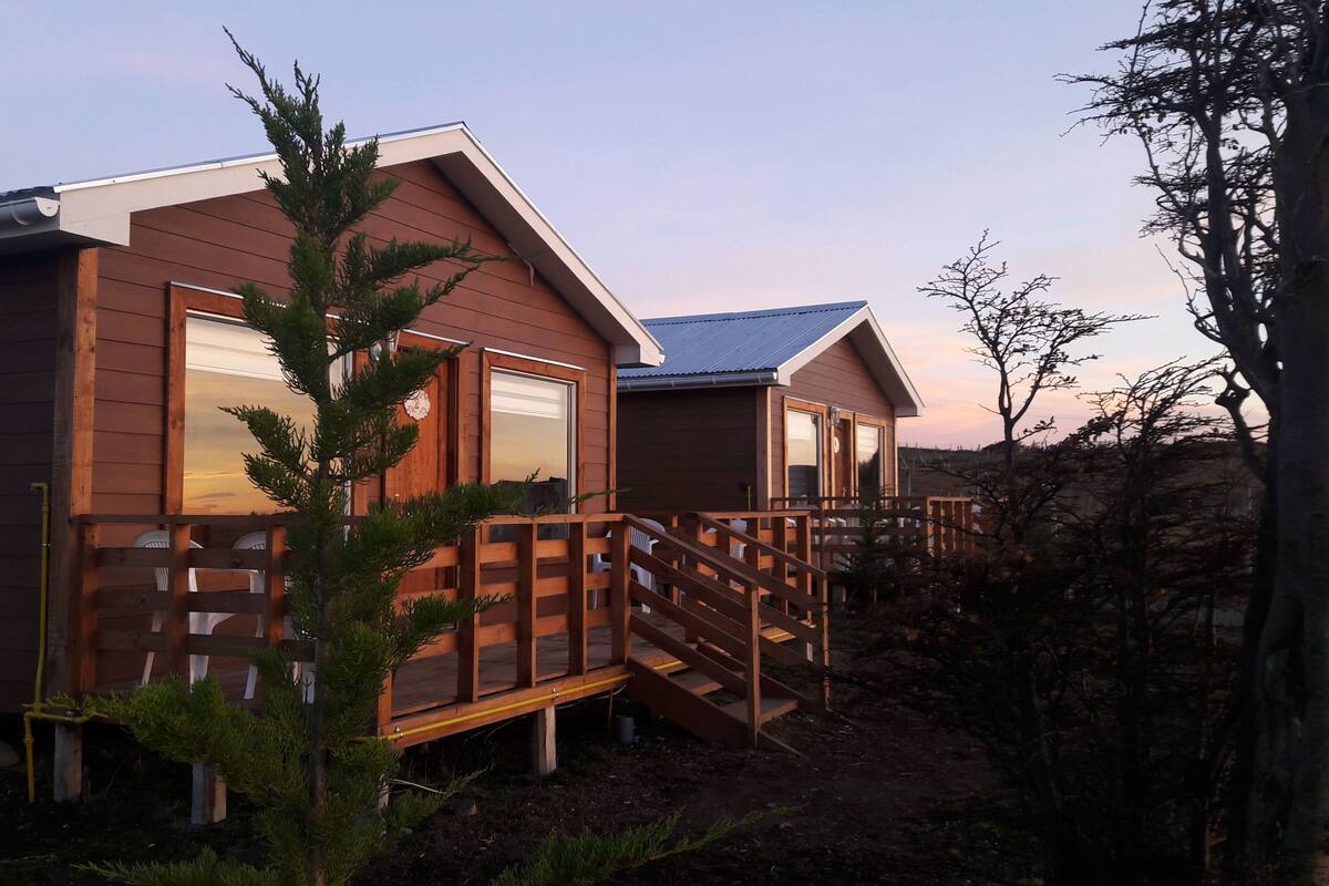 A wooden cabin with a deck and a small staircase leading to the entrance.