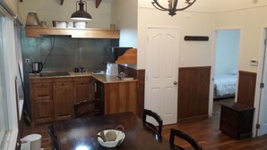 A compact kitchen with wooden cabinets, a dining table with chairs, and a small refrigerator. - Cabañas Cerro Las Piedras (Punta Arenas)