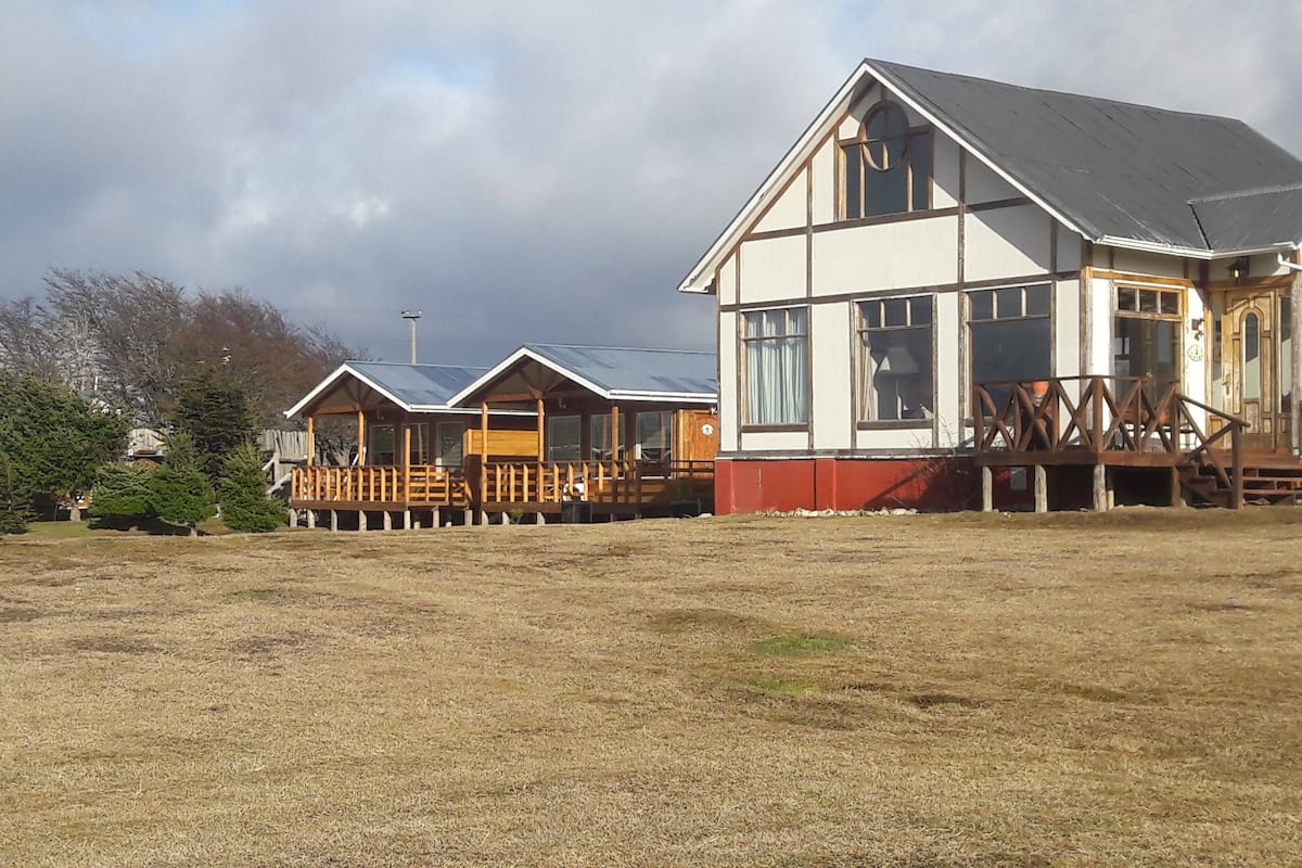 A row of wooden cabins with a large house in the foreground.