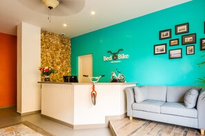 Een receptiegedeelte met een blauwgroene wand, een accentwand van steen, een receptiebalie, een bank en ingelijste foto's aan de muur.