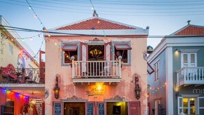 A two-story building with a balcony and outdoor seating area. - Bed & Bike Curacao Hostel (Willemstad)
