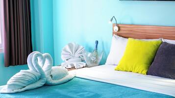 A neatly made bed with a blue bedspread, a wooden headboard, and pillows in yellow and gray.
