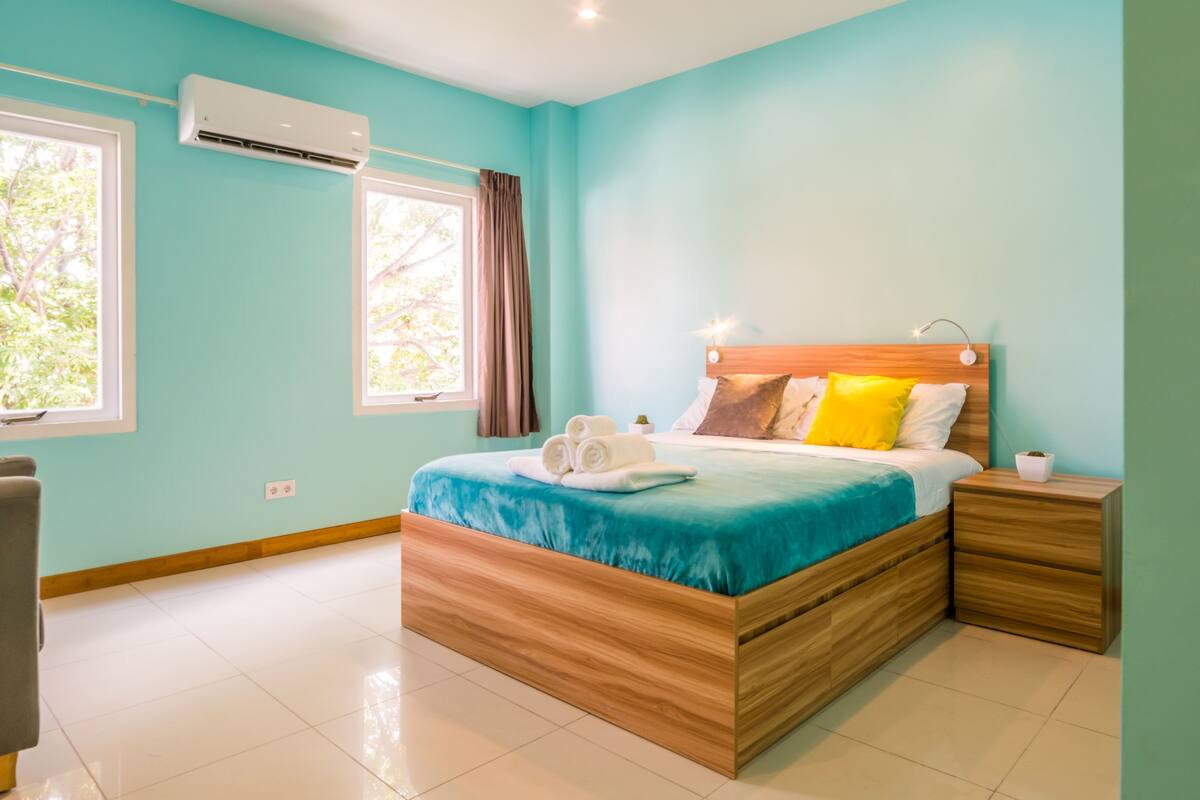 Ein modernes Schlafzimmer mit einem hölzernen Bett, einem Nachttisch und einer Klimaanlage.