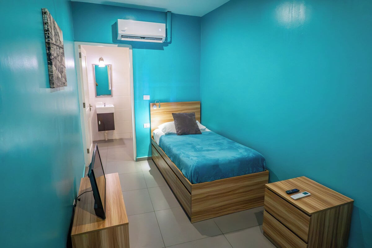 Une chambre à coucher comprenant un lit, une table de chevet, une commode et un appareil de climatisation.