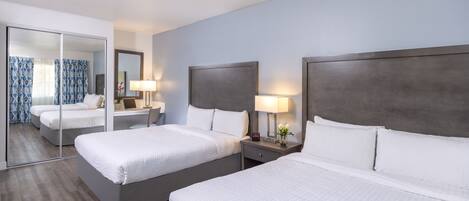 Een hotelkamer met twee bedden, een grote spiegel en bedlampjes.