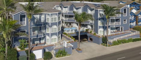 A multi-story residential building with balconies, a swimming pool, and a garage.