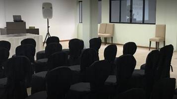 A conference room with rows of chairs, a podium, a laptop, and a speaker on a tripod.