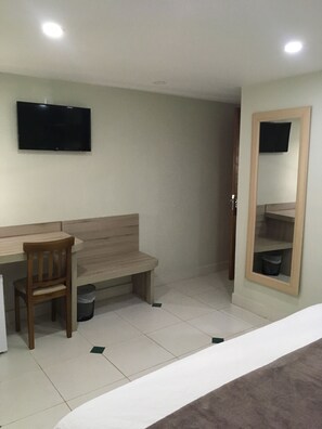 A room with a bed, a desk, a chair, a TV mounted on the wall, and a mirror. - Princesa Isabel Pousada & Hotel - Rua Teresa (Petrópolis)