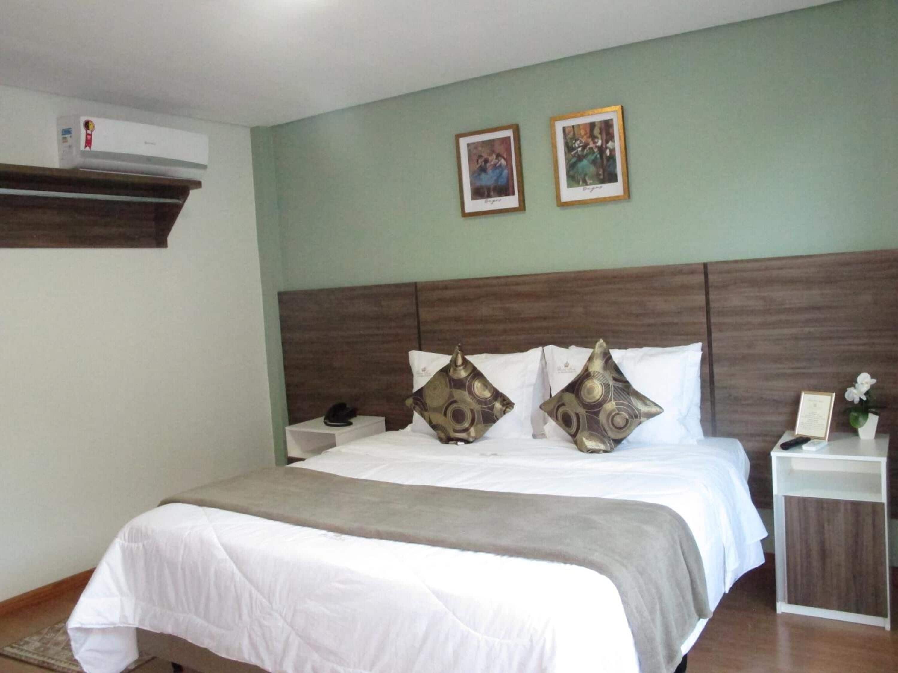 Camera d'albergo con un letto, un comodino e un condizionatore d'aria a parete.