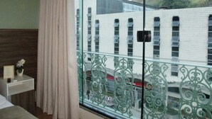 A hotel room with a balcony, a view of a building with multiple windows, and a mountainous landscape in the background. - Princesa Isabel Pousada & Hotel - Rua Teresa (Petrópolis)