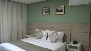 A hotel room with a bed, two bedside tables, a telephone, and an air conditioning unit on the wall. - Princesa Isabel Pousada & Hotel - Rua Teresa (Petrópolis)