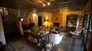 A cozy living room with a fireplace, a stone staircase, and a large window. - Bromelia Sabia & Cia (Teresópolis)
