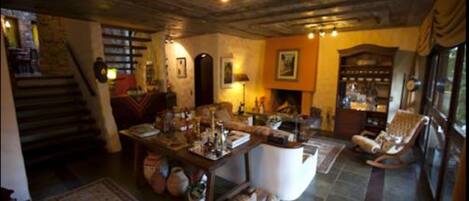 Un salon chaleureux avec une cheminée, un escalier en pierre et une grande fenêtre.