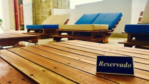 Una mesa de madera con un cartel que dice 'Reserved', sillones con cojines azules y una pared de piedra al fondo.