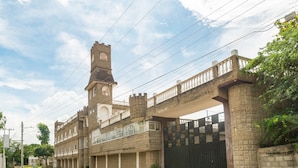 A large, historic building with a prominent clock tower and a balcony overlooking a street.