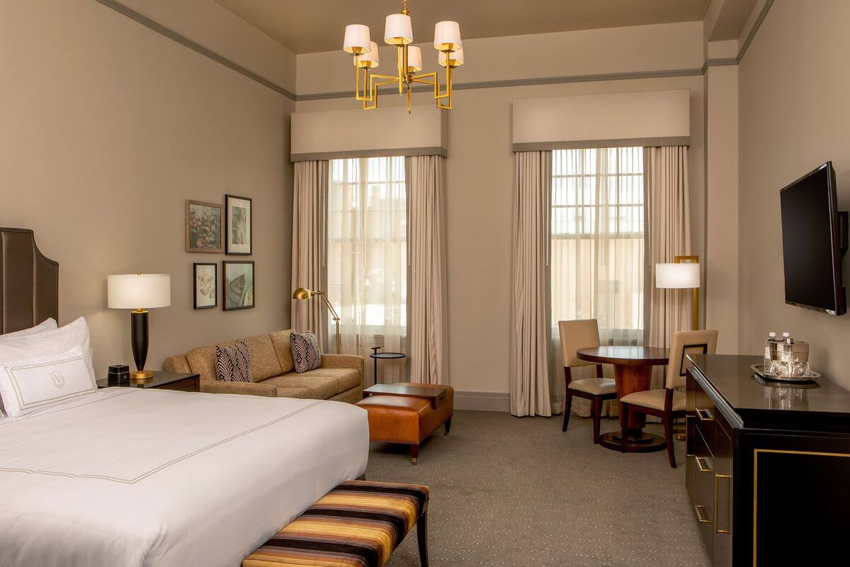 Een hotelkamer met een groot bed, een bank, een bureau en een televisie.
