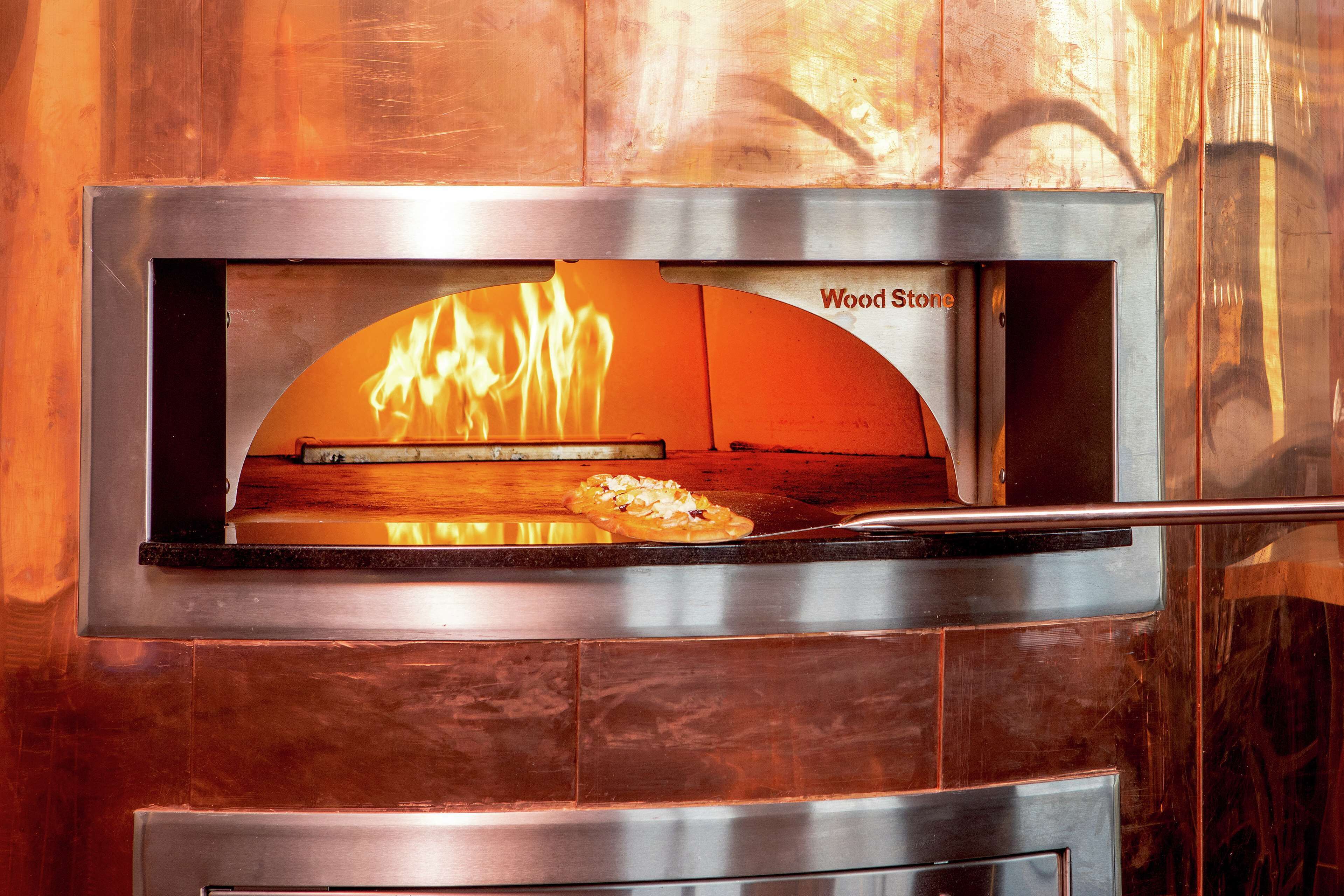 En træfyret pizzaovn med ild i.