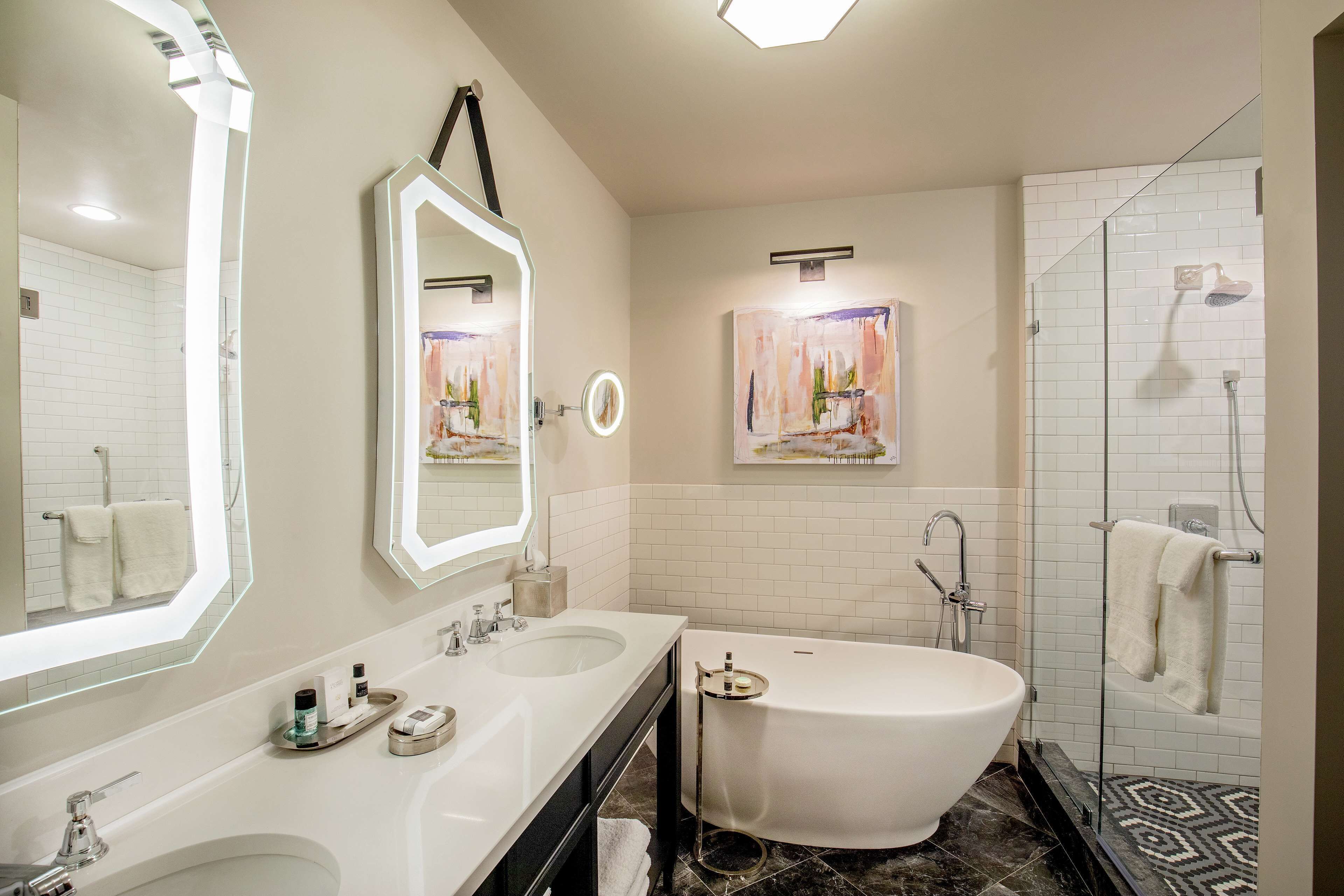 A modern bathroom with a freestanding bathtub, dual sinks, and a large mirror.