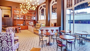 Un café acogedor con suelo de patrón hexagonal, barra de madera y diversas opciones de asientos, incluyendo mesas y sillas.
