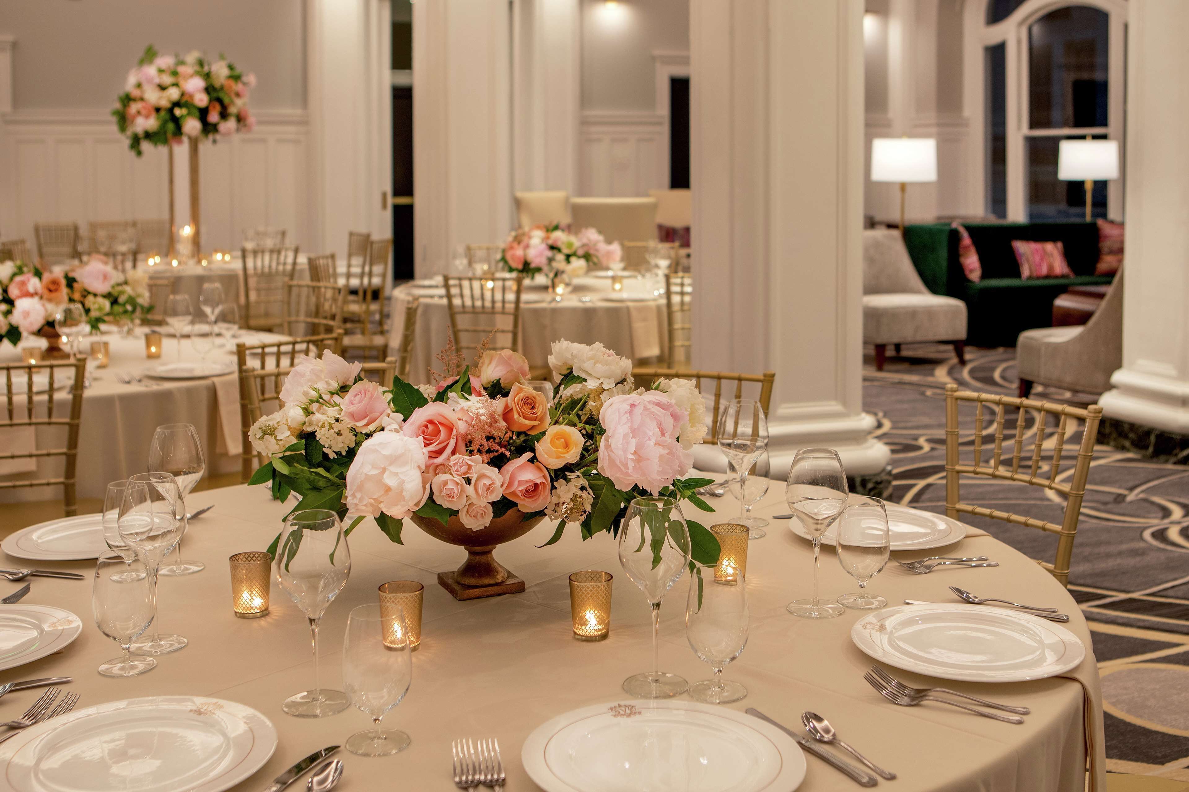 A formal dining area with round tables, white tablecloths, and floral centerpieces.