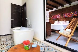 Ein Badezimmer mit einer Badewanne, einem Waschbecken und einem Holzstuhl mit Handtüchern.