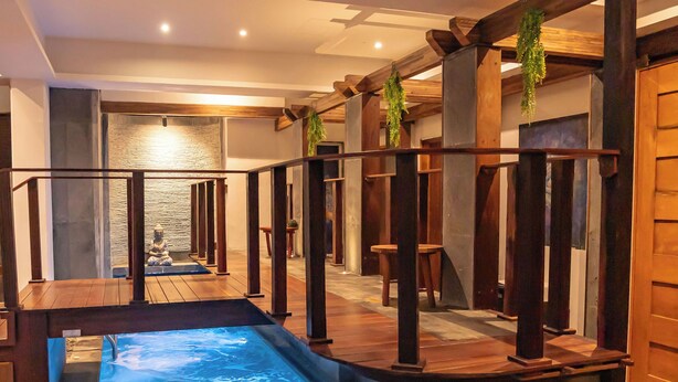 Uma área de spa com hidromassagem, deck de madeira e assentos de pedra.