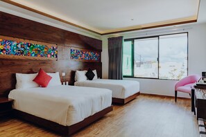 Une chambre d’hôtel avec deux lits, une tête de lit en bois, une grande fenêtre donnant sur un beau paysage et un bureau avec une chaise.