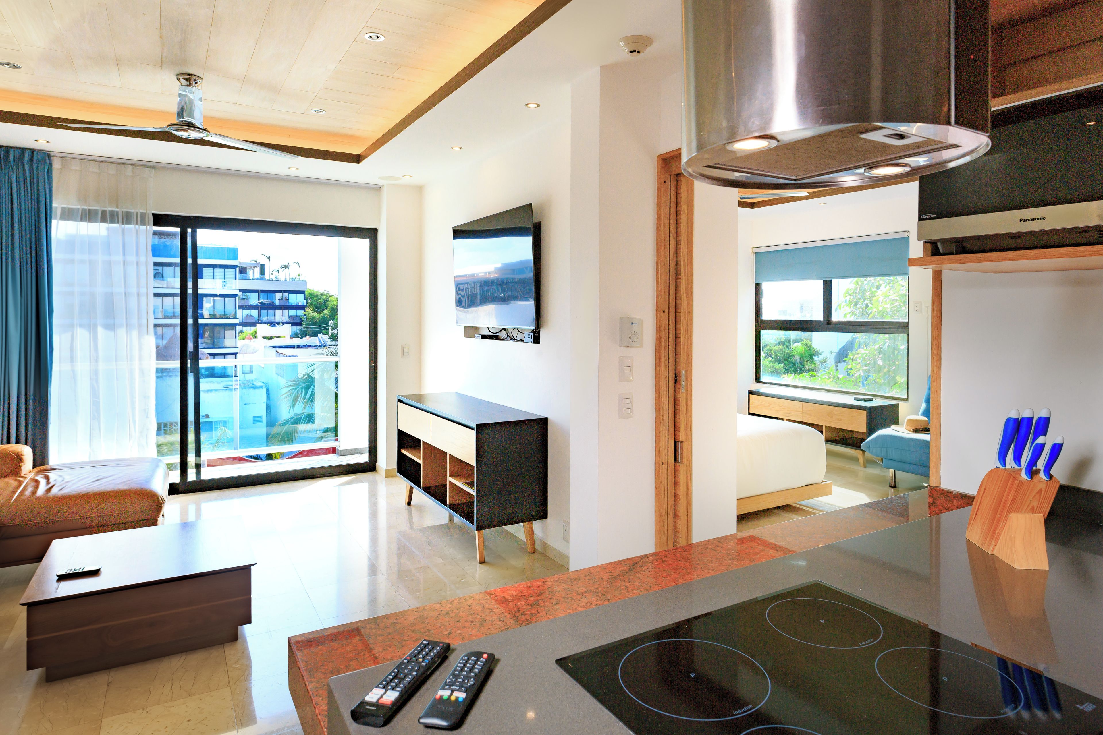 Una sala de estar moderna con un televisor de pantalla plana, un sofá, una mesa de centro y una cocina con estufa.