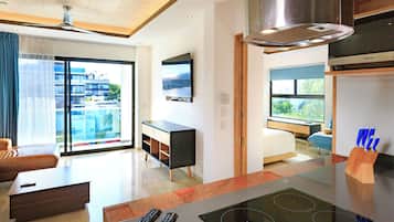 Una sala de estar moderna con un televisor de pantalla plana, un sofá, una mesa de centro y una cocina con estufa.