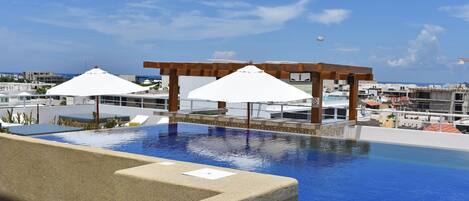 Alberca al aire libre, sombrillas en la alberca y camastros