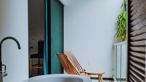 Casa de banho com banheira, uma cadeira e chão estampado.
