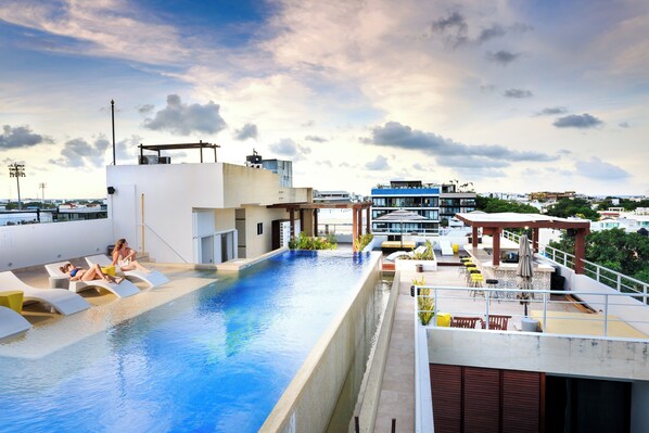 Une piscine sur le toit, avec des chaises longues et un espace bar.