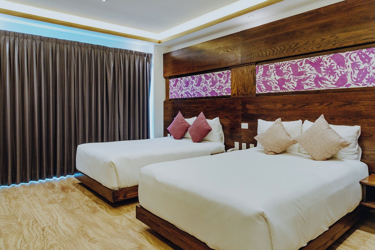 A hotel room with two beds, wooden headboard, and a large window with curtains.