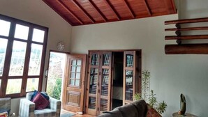 Una habitación con techo de madera, un ventanal grande, una puerta con paneles de vidrio y un sofá.