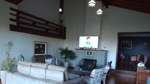 Una sala de estar con chimenea, un sofá, una televisión y un comedor.